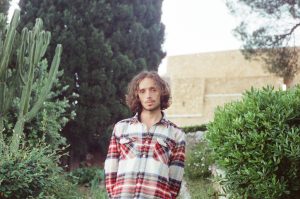 man in blouse standing in between trees